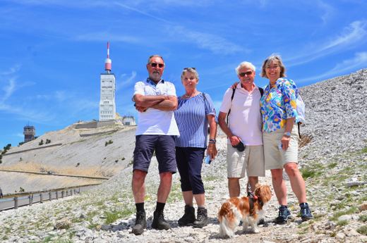 Quatre promeneurs avec un chien roux et blanc devant la tour du Ventoux.