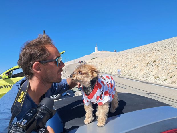 Un photographe et un petit chien au maillot à pois, devant le sommet.
